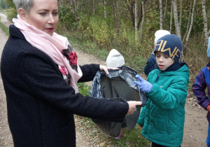 dzieci wrzucają znalezione śmieci do worka